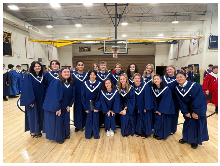 MTHS chorus posing in robes in a gym